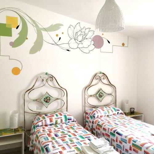 アックアペンデンテにあるCasa Girolamoの花の壁が飾られたベッドルーム内のベッド2台