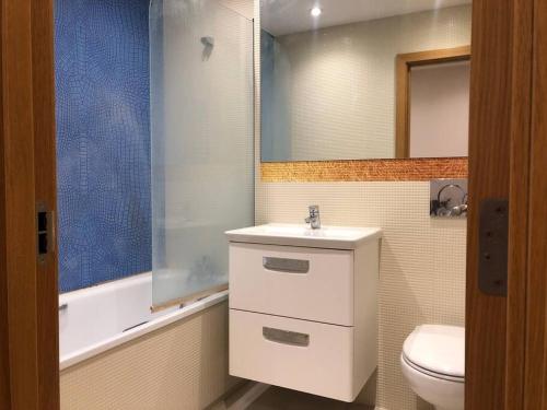 een badkamer met een wastafel, een toilet en een spiegel bij Flat in North Acton in Londen