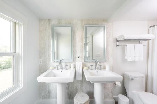 a white bathroom with two sinks and a toilet at White Moose Inn in Washington, Virginia