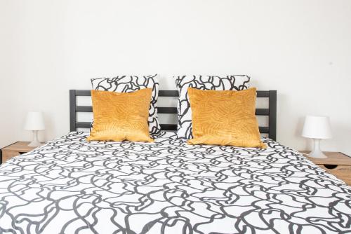 a bedroom with a black and white bed with two orange pillows at L'Escapade Mulhousienne in Mulhouse