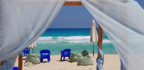 een groep stoelen en parasols op het strand bij Coronado North Coast Chalet Sea view for Families Only in El Dab‘a