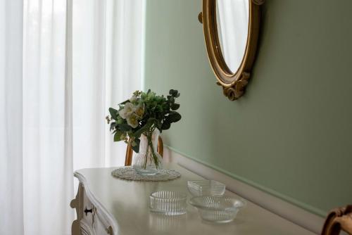 a vase of flowers on a table with a mirror at Dimora del Castellano GREEN HOUSE in Gioia del Colle