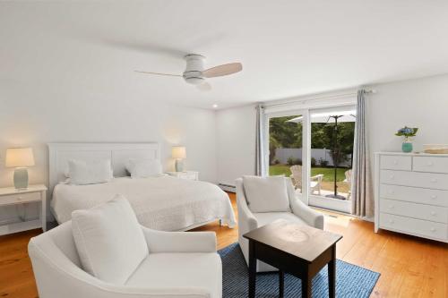 ein weißes Schlafzimmer mit einem Bett und zwei Stühlen in der Unterkunft 2 Bicycles Provided! Cape Cod Cottage with Deck in Orleans