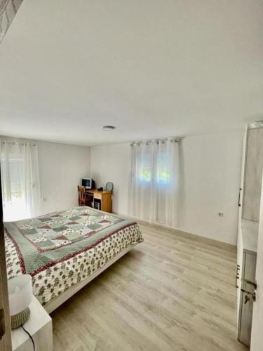 a white bedroom with a bed and a wooden floor at Holiday house ISIDORA in Danilovgrad