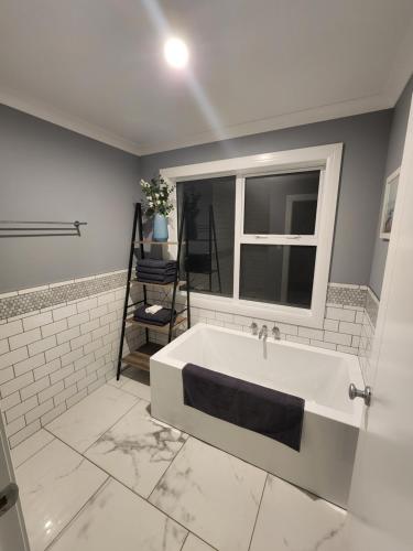 a bathroom with a bath tub and a window at Country Hamptons Coastal Chic with Heated Pool in Ruakaka