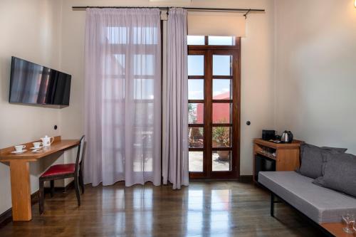 a living room with a couch and a table and a window at Mosaic Venetian Harbour Suites in Chania Town