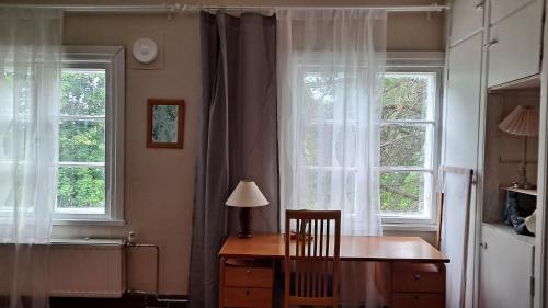 a room with two windows and a table with a lamp at Salonsaaren Pappila in Terälahti