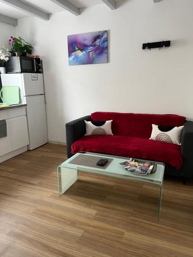 een woonkamer met een rode bank en een salontafel bij Petit nid Catalan , 10 minutes des plages in Perpignan