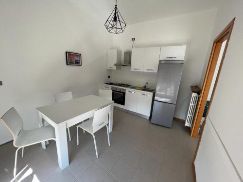- une cuisine blanche avec une table, des chaises et un réfrigérateur dans l'établissement Terrazza sul lago (CIR 017085-LNI-00027), à Iseo