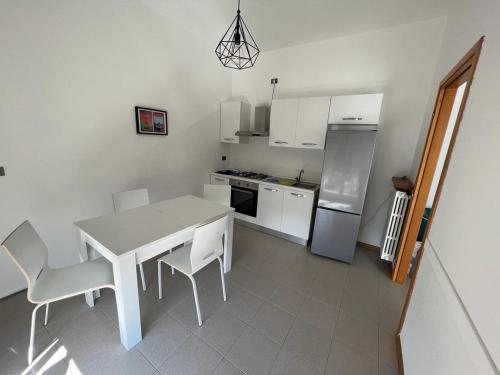 a white kitchen with a table and chairs and a refrigerator at Terrazza sul lago (CIR 017085-LNI-00027) in Iseo