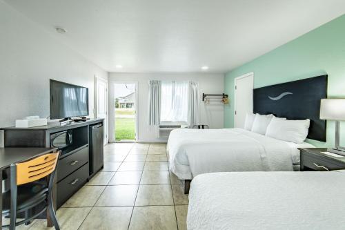 a hotel room with two beds and a flat screen tv at Everglades City Motel - Everglades Adventures Inn in Everglades City