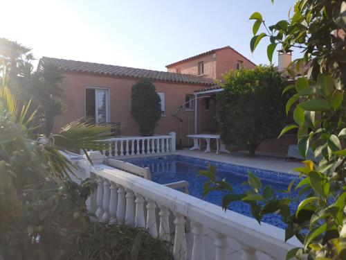 een huis met een zwembad en een wit hek bij villa avec piscine privée in Pia