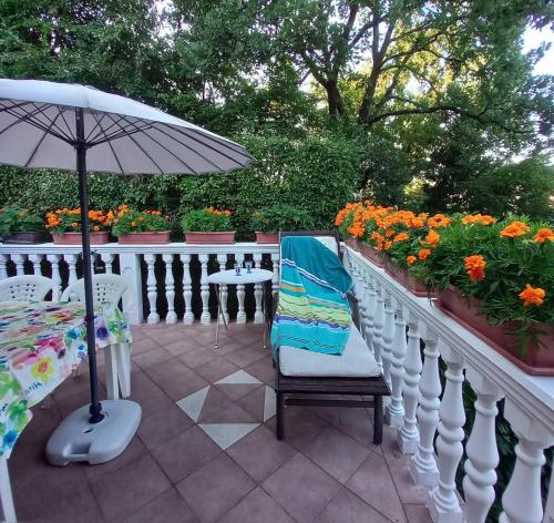 a patio with a table and an umbrella and flowers at Villa Maria in Opatija