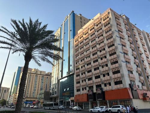 a palm tree in front of a tall building at فندق كنان العزيزية Kinan Al Azizia Hotel Makkah in Mecca