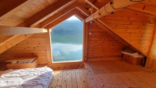 an attic room with a bed and a large window at Lake house Perucac in Bajina Bašta