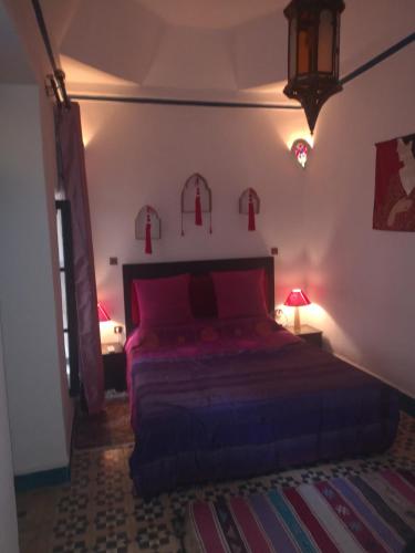 ein Schlafzimmer mit einem Bett mit roten Kissen und einer Lampe in der Unterkunft Riad El Badii in Marrakesch
