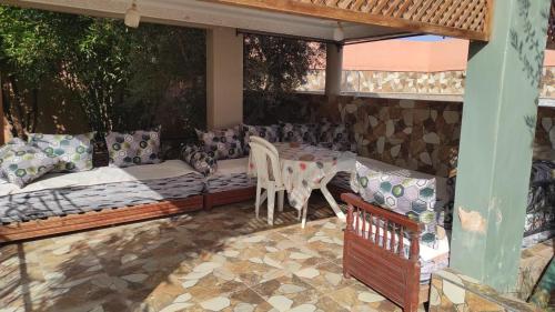een patio met een bank en een tafel en stoelen bij Magnifique ferme avec piscine in Marrakesh