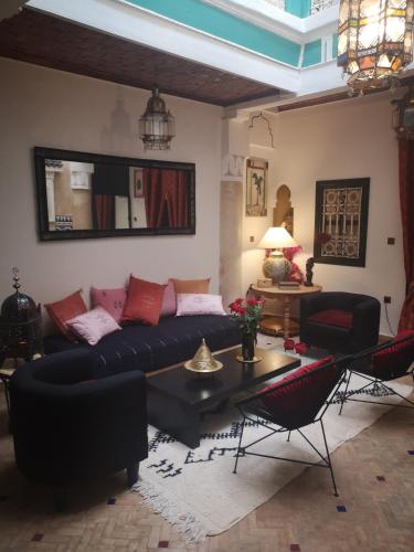 ein Wohnzimmer mit einem Sofa, einem Tisch und Stühlen in der Unterkunft Riad El Badii in Marrakesch