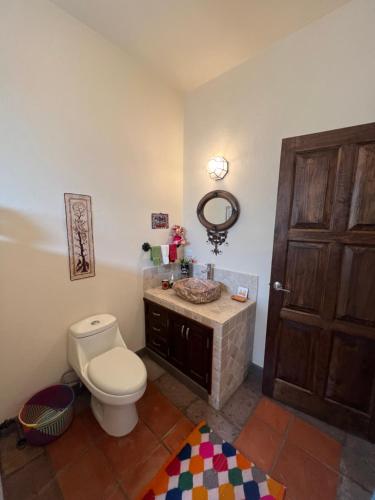 W łazience znajduje się toaleta oraz umywalka z lustrem. w obiekcie casa la vida es buena w mieście San Miguel de Allende