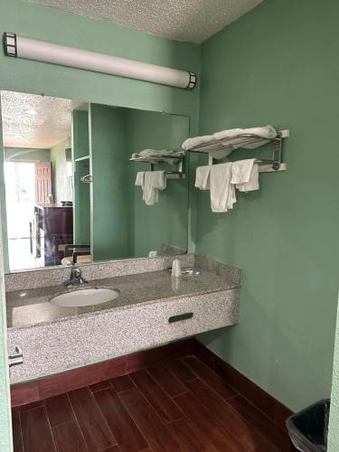 La salle de bains est pourvue d'un lavabo et d'un miroir. dans l'établissement Roadside Inn, à Floresville