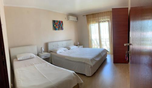 Guest House Budva في بودفا: غرفة نوم بسريرين وباب بها نافذة