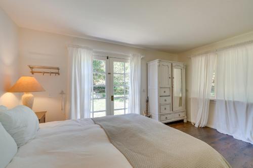 1 dormitorio blanco con 1 cama grande y ventanas en Farmhouse-Chic Carpinteria Cottage with Pool Access, en Carpinteria