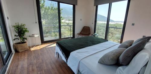 a bedroom with a large bed and large windows at Villa Olea - Relax in nature in Fethiye