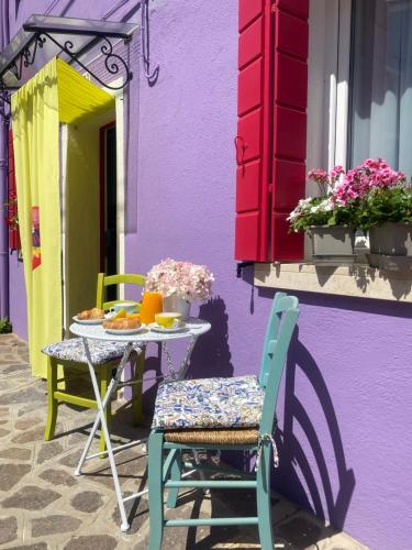 une table et des chaises devant un bâtiment violet dans l'établissement Casa Bella, à Burano