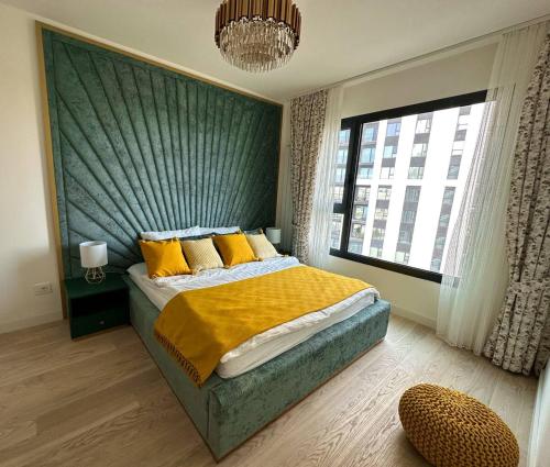 ein Schlafzimmer mit einem Bett mit gelben Kissen und einem Fenster in der Unterkunft SuprStay - Belgrade Waterfront Luxury Apartment in Belgrad