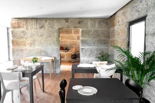 una sala da pranzo con tavoli, sedie e un muro di mattoni di CASA DAS FONTELAS a Castelo de Paiva