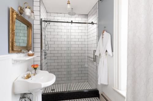 a white bathroom with a sink and a shower at Rosemont Inn in Utica