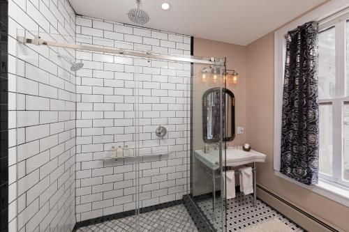 a bathroom with a shower with a sink and a mirror at Rosemont Inn in Utica