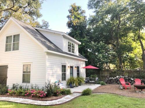 a white house with a yard with chairs and a table at Liz Lane Cottage- entire guesthouse in Charleston