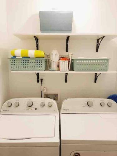 a laundry room with two washers and baskets on shelves at Liz Lane Cottage- entire guesthouse in Charleston