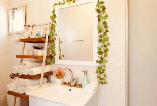 La salle de bains est pourvue d'un lavabo, d'un miroir et de serviettes. dans l'établissement דיזנגוף סנטר חניה פרטית מרפסת שמש, à Tel Aviv