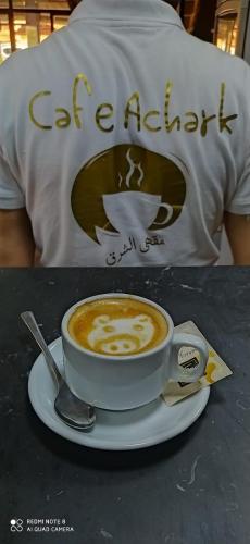 a cup of coffee on a plate with a spoon at Hotel Achark in Bou Arfa