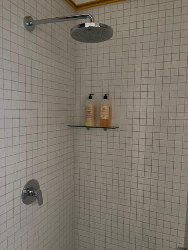 2 botellas en un estante en un baño alicatado en Casa Amari en Ciudad de México