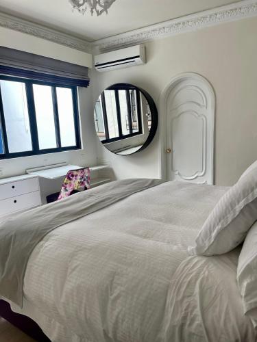 a white bedroom with a large bed and a mirror at Casa Amari in Mexico City