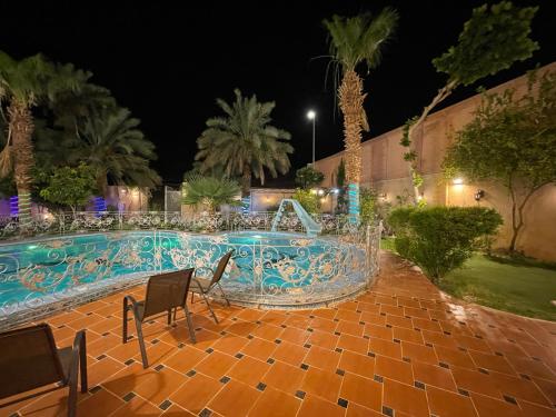 a swimming pool at night with chairs and palm trees at استراحة زين in Al Madinah