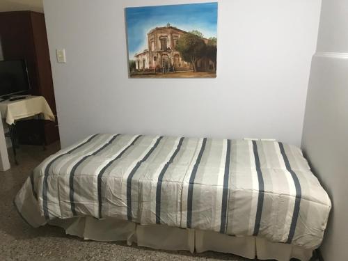 1 cama en una habitación con un cuadro en la pared en Boulevard Alsina 5 en San Antonio de Areco
