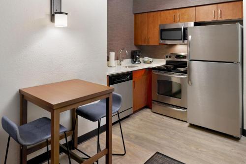 eine kleine Küche mit einem Tisch und einem Kühlschrank aus Edelstahl in der Unterkunft Residence Inn Asheville Biltmore in Asheville