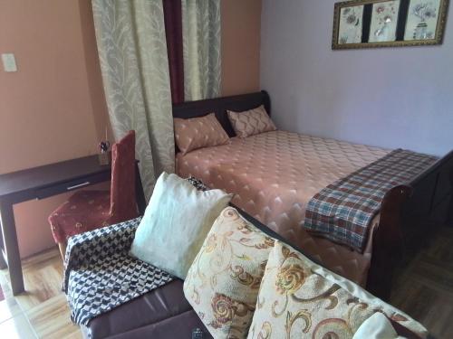 a small bedroom with a bed and a couch at palms in Jerningham Junction