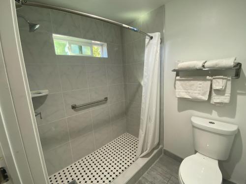 a white bathroom with a shower and a toilet at Royale Inn Motel in Whittier