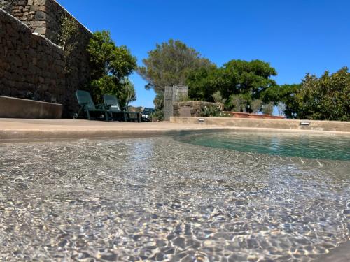 a pool of water with two chairs next to it at Dammuso i Pini di Kaddiuggia (CIR19081014C224053) & Dammuso di Mena (CIR 19081014C224052 in Pantelleria