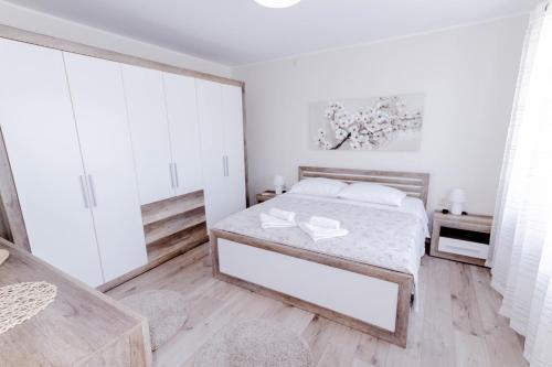 a white bedroom with a bed and a wooden floor at Villa Kata in Vrpolje