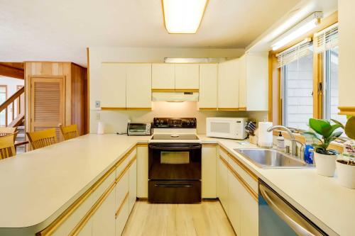 a kitchen with white cabinets and a sink at Woodsy Big Bass Lake Hideaway with Fire Pit and Deck! in Gouldsboro