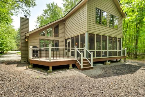 a small house with a large porch and a deck at Woodsy Big Bass Lake Hideaway with Fire Pit and Deck! in Gouldsboro
