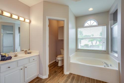 a bathroom with a tub and a toilet and a window at Sunny Fort Myers Home with Heated Pool! in Fort Myers