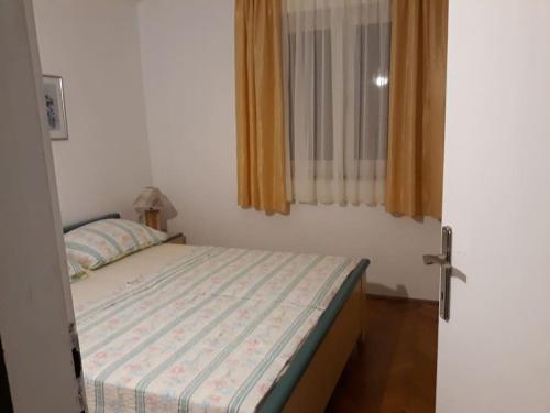 een kleine slaapkamer met een bed en een raam bij Apartman 1 in Omišalj