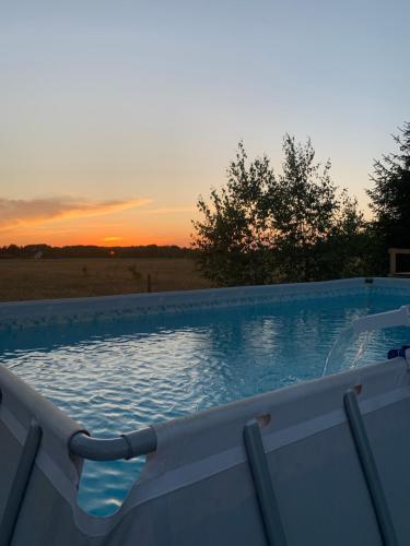 a swimming pool with the sunset in the background at Chatka Baby Agi in Cieciory